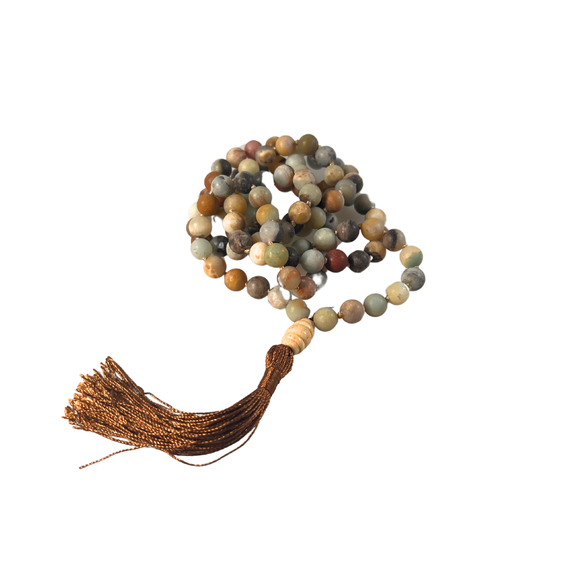 Eine handgeknüpfte Mala-Kette aus matten Amazonit-Perlen in sanften Naturtönen von Grün, Grau, Beige und Rotbraun. Die Kette ist spiralförmig gelegt und mit einer dunkel schimmernden Quaste sowie einer hellen Holz-Guru-Perle versehen. Das Schmuckstück ist freigestellt vor neutralem Hintergrund dargestellt und eignet sich ideal für Meditation, Erdung und Momente der inneren Balance.