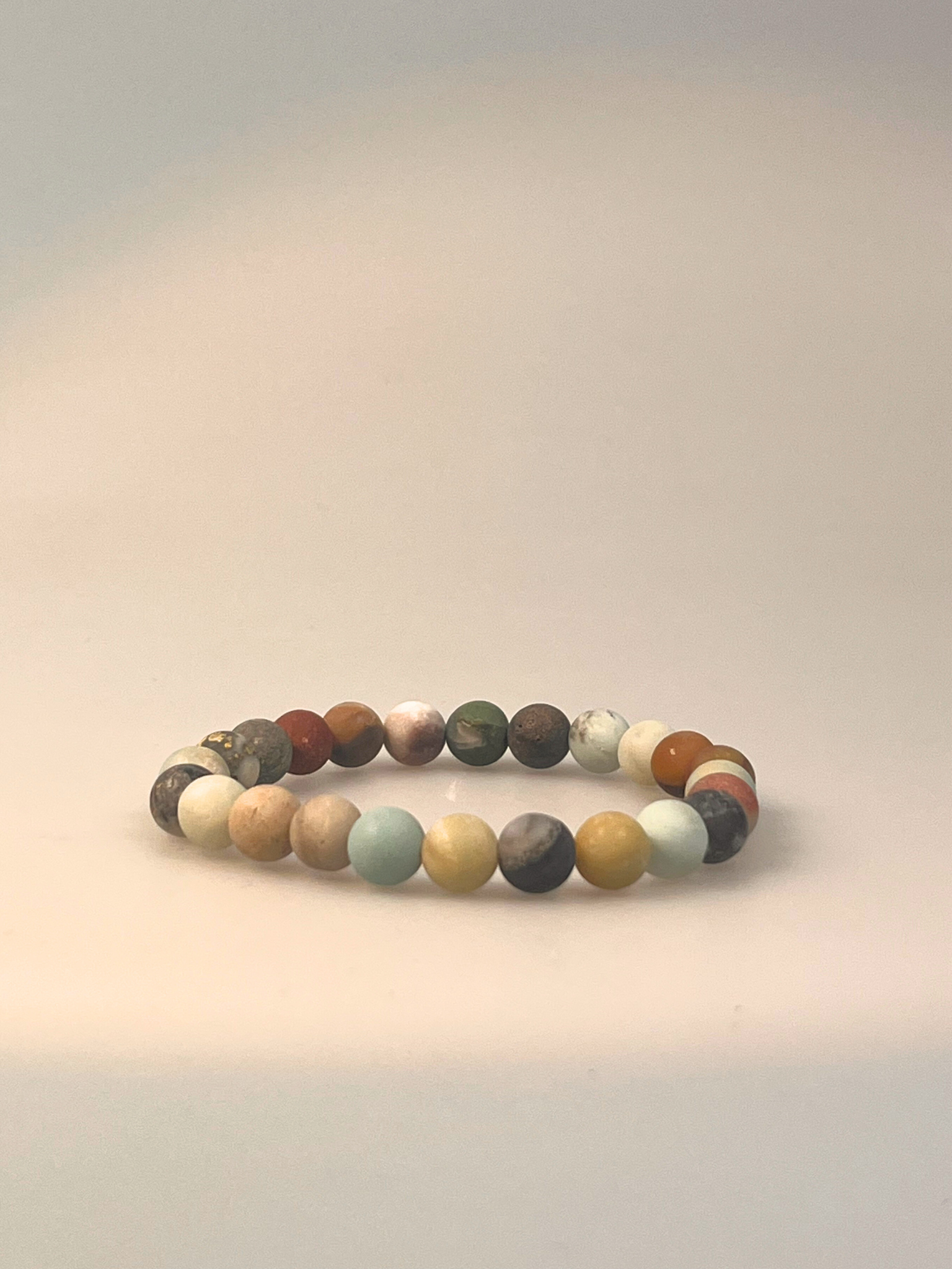 Ein elastisches Armband aus mattem Amazonit, bestehend aus gleichmäßig runden Edelsteinperlen in natürlichen Tönen von Hellgrün, Beige, Grau, Braun und sanften Blau-Nuancen. Das Armband ist freigestellt auf hellem Hintergrund dargestellt und wirkt erdend, beruhigend und vielseitig kombinierbar – ideal für Alltagsrituale oder als stilvolles Accessoire mit Bedeutung.