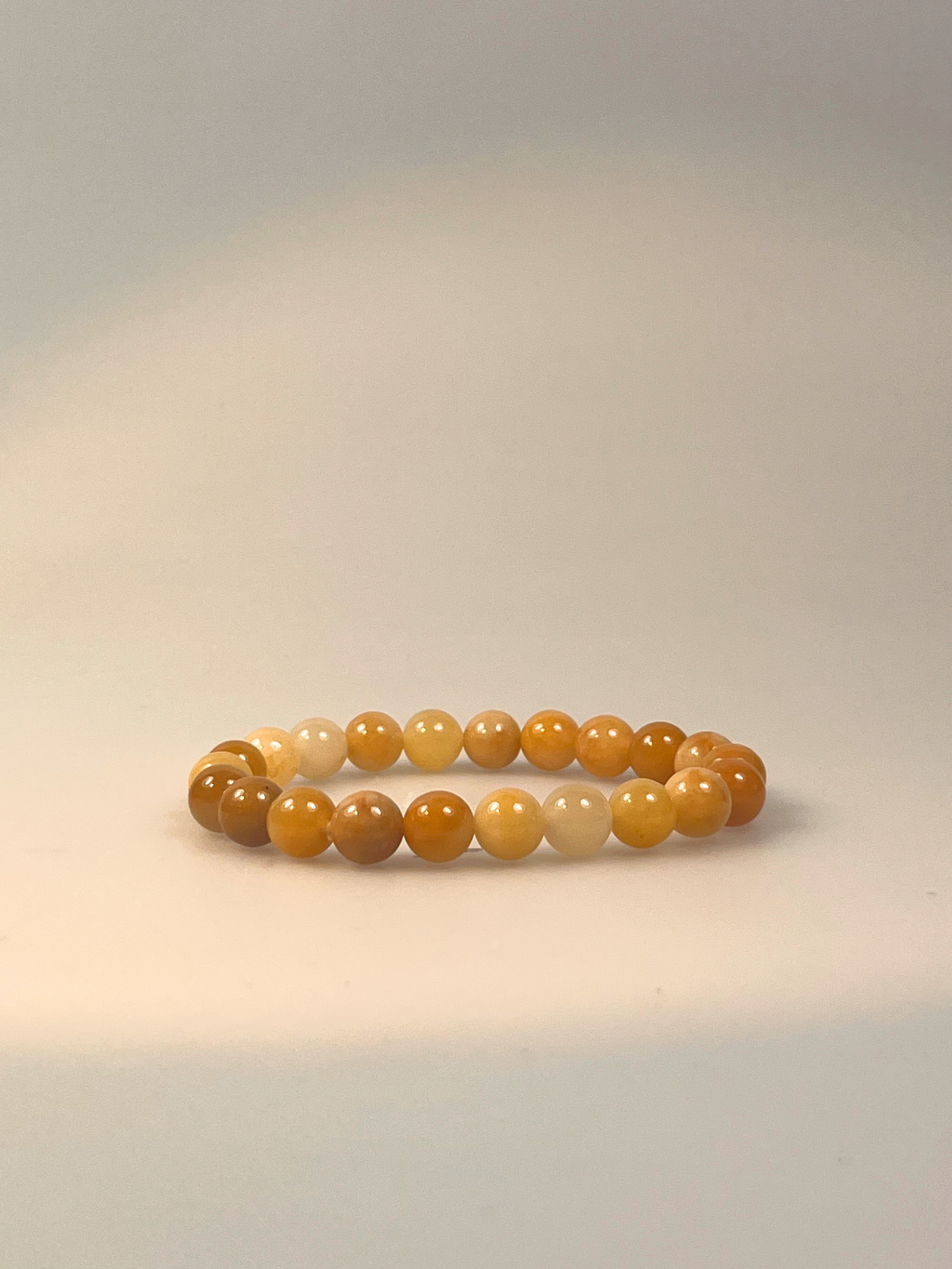 Ein elastisches Armband aus runden, polierten Honig-Calzit-Perlen in warmen Gelb-, Creme- und Bernsteintönen. Das Armband liegt mittig auf einem transparenten bzw. freigestellten Hintergrund, sodass der Fokus ganz auf den harmonischen Farbabstufungen und der glatten, glänzenden Oberfläche der Steine liegt. Ideal als natürlicher Begleiter für Alltag, Meditation oder als symbolisches Geschenk für Kraft und Ausgleich.
