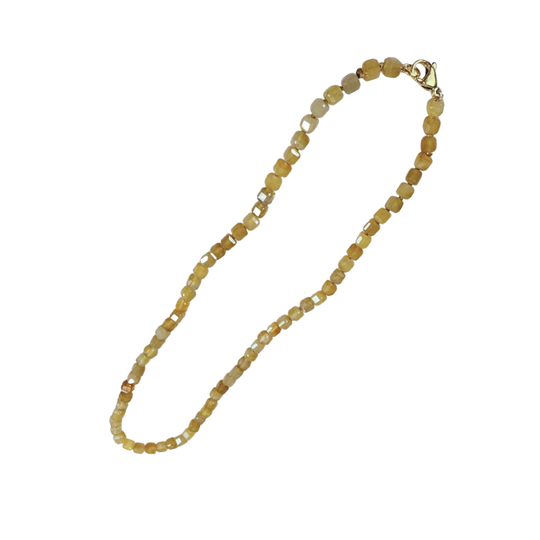 Eine feine Halskette aus facettierten Calcit-Edelsteinen in warmen Gold- und Honigtönen. Die quadratisch geschliffenen Steine sind gleichmäßig aneinandergereiht und funkeln bei jeder Bewegung dezent im Licht. Abgeschlossen wird die Kette mit einem goldfarbenen Verschluss – ein stilvolles Schmuckstück voller Sonnenenergie, das Leichtigkeit und Lebensfreude ausstrahlt. Ideal als Statement für Selbstvertrauen und Wärme.