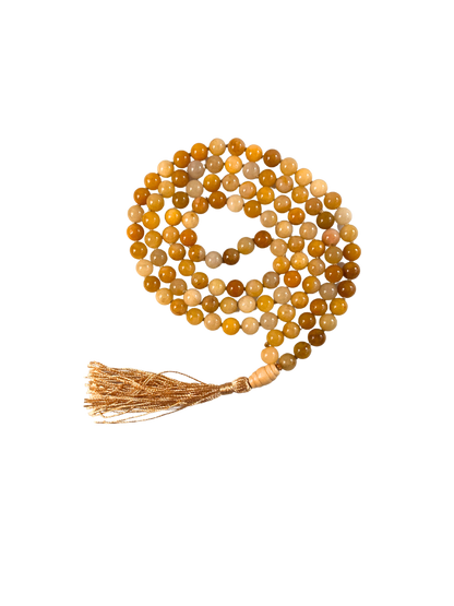 Eine handgeknüpfte Mala-Kette aus polierten Honigcalcit-Perlen in warmen Gelb- und Goldtönen, spiralförmig gelegt und mit einer goldschimmernden Quaste sowie einer glatten Guru-Perle aus hellem Holz veredelt. Das Schmuckstück ist freigestellt auf hellem Hintergrund dargestellt und eignet sich ideal für Meditation, spirituelle Rituale oder als energetisches Accessoire mit sonniger Ausstrahlung.
