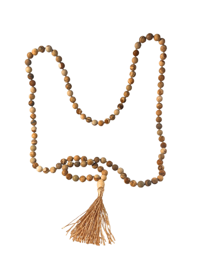 Freigestellte Mala-Kette aus Landschaftsjaspis mit 108 matten, sandfarbenen bis erdbraunen Edelsteinperlen in natürlicher Maserung. Die Kette ist handgeknüpft, verfügt über eine helle Holz-Guru-Perle und ist mit einer goldbeigen Quaste vollendet. Ideal für Meditation, Achtsamkeit und als spirituelles Schmuckstück mit erdender Wirkung.