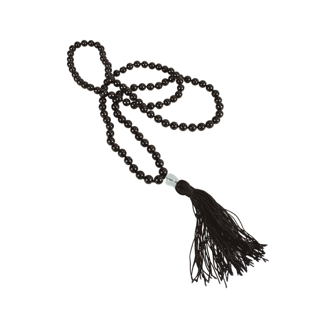 Freigestellte Mala-Kette aus schwarzem Turmalin mit gleichmäßig runden, glänzenden Edelsteinperlen. Die Kette ist mit einer hälzernen Guru-Perle aus und einer schwarzen Seidenquaste veredelt. Die Perlen sind in traditioneller Weise geknüpft und ergeben eine kraftvolle Kombination für Schutz und Zentrierung. Ideal für Meditation, Rituale oder als hochwertiges spirituelles Schmuckstück.