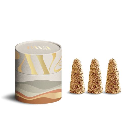 Auf dem Bild sind drei naturbelassene Räucherkegel sowie eine dekorative PAVA FUMA Design-Dose zu sehen. Die Kegel bestehen sichtbar aus groben Kräutern und Harzen in warmer, goldbrauner Farbe. Die runde Dose im Hintergrund ist in Naturtönen gestaltet – mit einem modernen, geschwungenen Muster in Beige, Sand, Grau und Ocker. Das Produkt vermittelt Natürlichkeit, Ästhetik und eine hochwertige Duftkomposition.