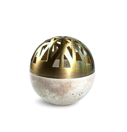 Design-Räuchergefäß in Kugelform aus echtem Travertinstein mit handgearbeitetem Deckel aus gebürstetem Messing. Die goldfarbene Kuppel mit stilisiertem Cut-Out-Muster sorgt für elegante Lichtspiele beim Räuchern. Die harmonische Kombination aus naturbelassenem Stein und edlem Metall macht dieses Gefäß zum stilvollen Mittelpunkt jeder Duftzeremonie – modern, hochwertig und ausdrucksstark in der Form. Ideal für Kohleräucherungen oder zur ästhetischen Raumgestaltung. Freigestellt vor hellem Hintergrund.