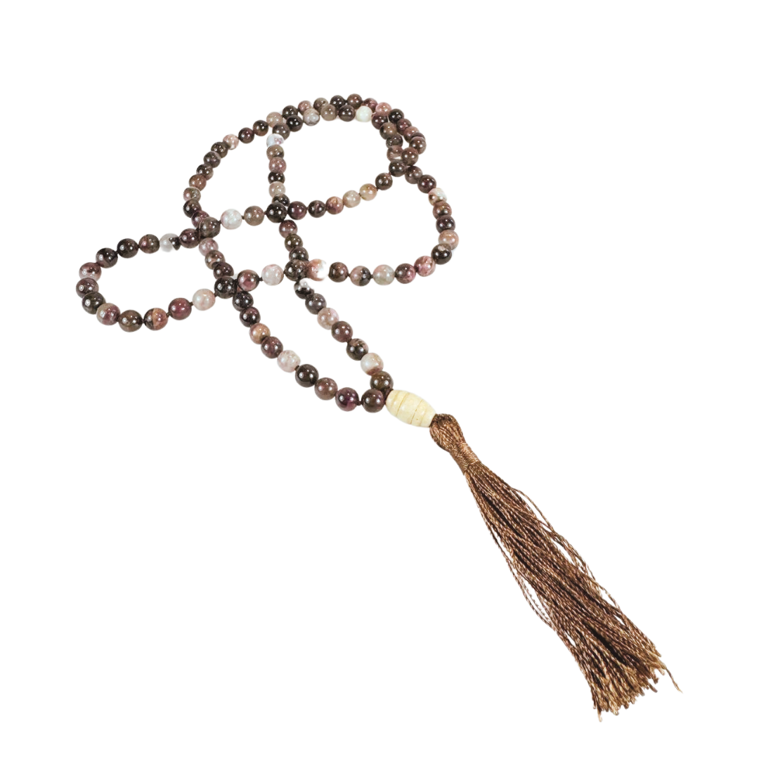 Handgeknüpfte Mala-Kette aus glatten Turmalinperlen in erdigen Rot-, Braun- und Beigetönen. Die 108 Perlen sind kunstvoll mit einer hellen Guru-Perle und einer glänzenden braunen Quaste vollendet. Die Kette liegt locker geschwungen auf schwarzem Hintergrund. Ideal für Meditation, Achtsamkeit oder als ausdrucksstarkes Schmuckstück mit spiritueller Tiefe.