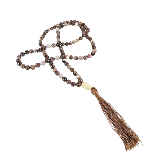 Handgeknüpfte Mala-Kette aus glatten Turmalinperlen in erdigen Rot-, Braun- und Beigetönen. Die 108 Perlen sind kunstvoll mit einer hellen Guru-Perle und einer glänzenden braunen Quaste vollendet. Die Kette liegt locker geschwungen auf schwarzem Hintergrund. Ideal für Meditation, Achtsamkeit oder als ausdrucksstarkes Schmuckstück mit spiritueller Tiefe.